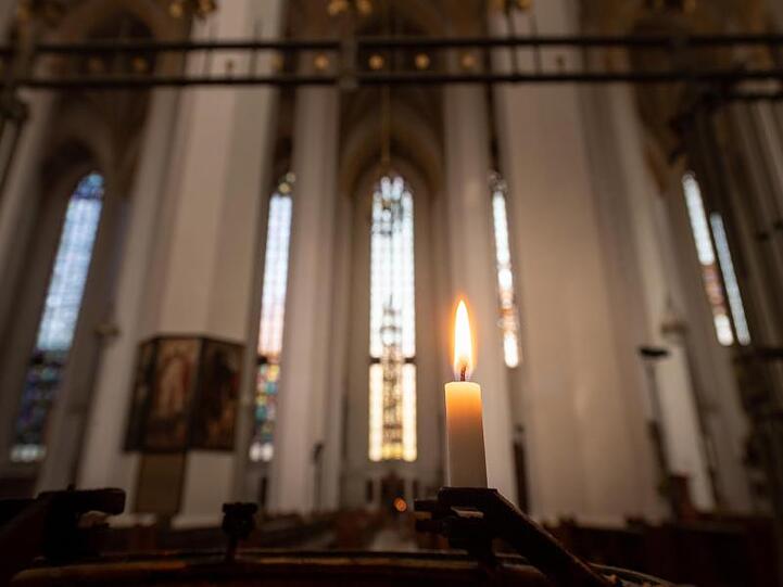 Ein einzelne Kerze brennt in der Frauenkirche. Foto: Peter Kneffel/dpa/Archivbild