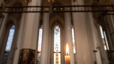 Ein einzelne Kerze brennt in der Frauenkirche. Foto: Peter Kneffel/dpa/Archivbild