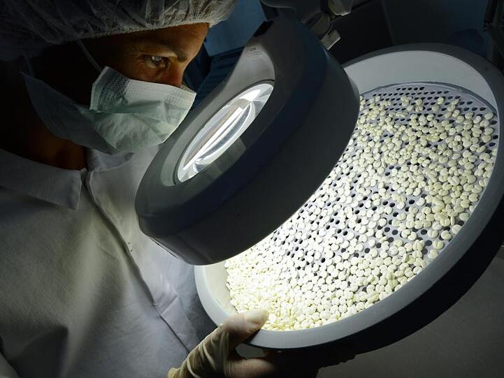 Eine Merck-Mitarbeiterin bei einer Sichtkontrolle in der Pharma-Produktion.