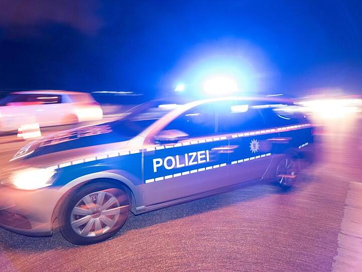 Ein Polizeifahrzeug steht mit Blaulicht auf der Straße.