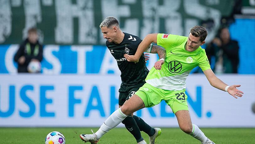 Wolfsburgs Jonas Wind (r) im Zweikampf mit dem Bremer Marco Friedl.