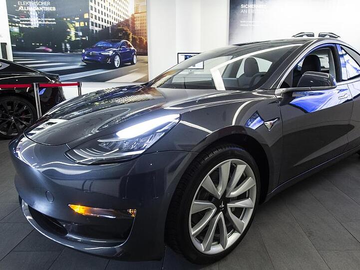 Das Elektroauto Model 3 von Tesla steht in einem Ausstellungsraum.