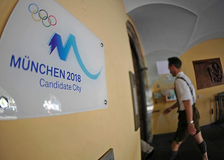 Ein Mann in Tracht geht am Sonntag an einem Werbeschild für die Olympiabewerbung Münchens vorbei in das Rathaus in Garmisch-Partenkirchen.