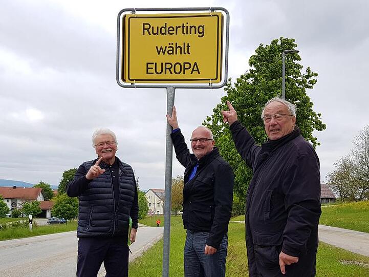 Konrad Kobler, Rudolf Müller und Joachim Rübenach stehen neben einem selbst gemachten Ortsschild mit der Aufschrift "Ruderting wählt Europa". Foto: Rudolf Müller