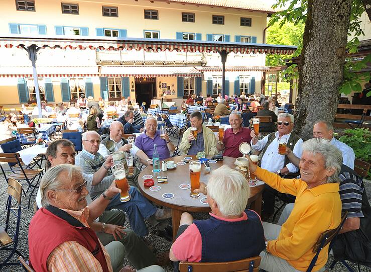 Hier kehrt man gern ein: Ein großer Tisch mit einer fröhlichen Runde &ndash; im Hintergrund das altehrwürdige Gasthaus.