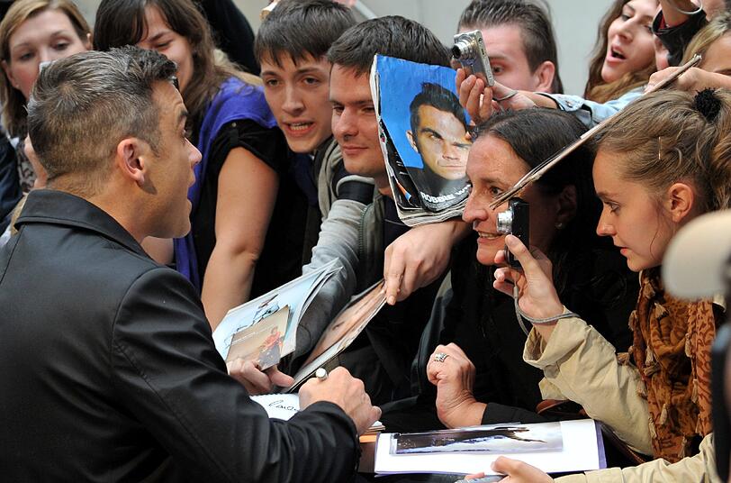 Weltstar im Fan-Gewusel: Robbie Williams verteilte Autogramme vor dem Mathäser-Kino.