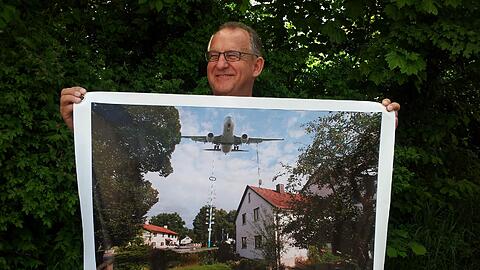"Grüße aus Attaching", steht auf dem Plakat mit der bedrohlichen Fotomontage, das Frank Spitzenberger von der Bürgerinitiative hält.