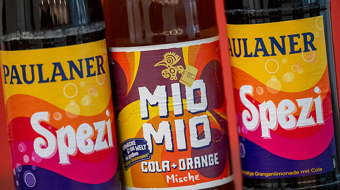 Zwei Spezi-Flaschen des Herstellers Paulaner stehen neben einer Flasche Mio-Mio-Cola-Orange-Mische (Mitte) des Herstellers Berentzen. Voraussichtlich am 5. August gibt es ein Urteil im Rechtsstreit zwischen Paulaner und Berentzen um das Farbdesign der Flasche.