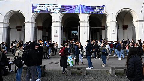 Studenten stehen vor dem Hauptgebäude der LMU.