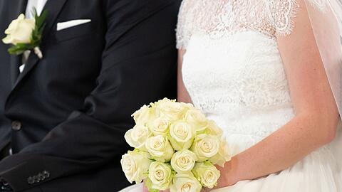 Ein Brautpaar sitzt während ihrer Trauung in der Kirche: In der Corona-Zeit hat ein Paar auf seine Hochzeit verzichtet - was ein Nachspiel  hat.