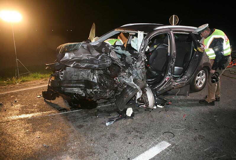 Ein Polizeibeamter schaut am 05.04.2014 in Neu-Ulm nach einem Verkehrsunfall in das beschädigtes Fahrzeug.