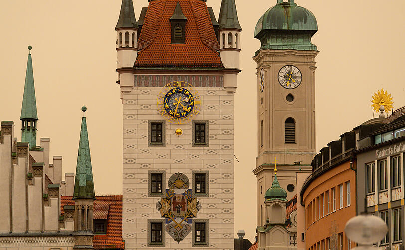 Altes Rathaus und Heilig-Geist-Kirche: Nach Angaben von Meteorologen trugen am Dienstag Südwestwinde Wüstensand zunächst nach Nieder- und Oberbayern und tauchten unter anderem München in ein bräunliches oder orangenes Licht.
