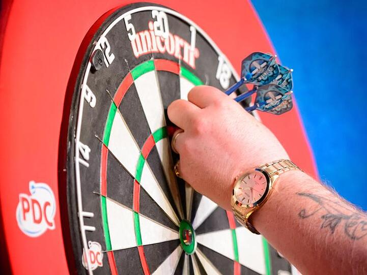Ein Dartspieler nimmt Pfeile vom Bord. Foto: Thomas Eisenhuth/dpa-Zentralbild/dpa/Symbolbild