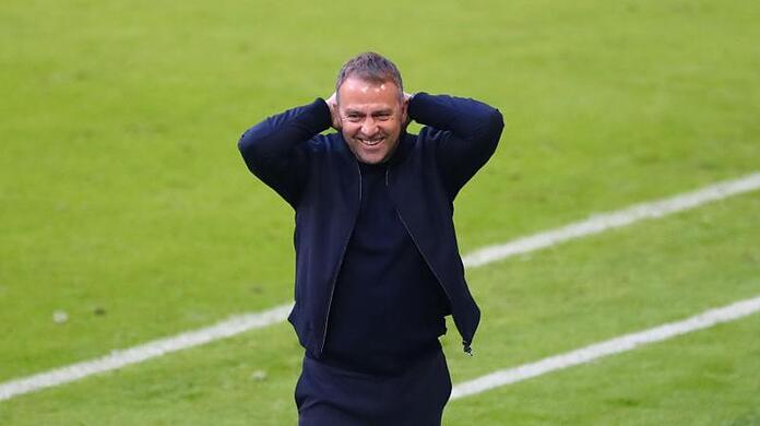Münchens Trainer Hansi Flick fasst sich lächelnd an den Kopf.