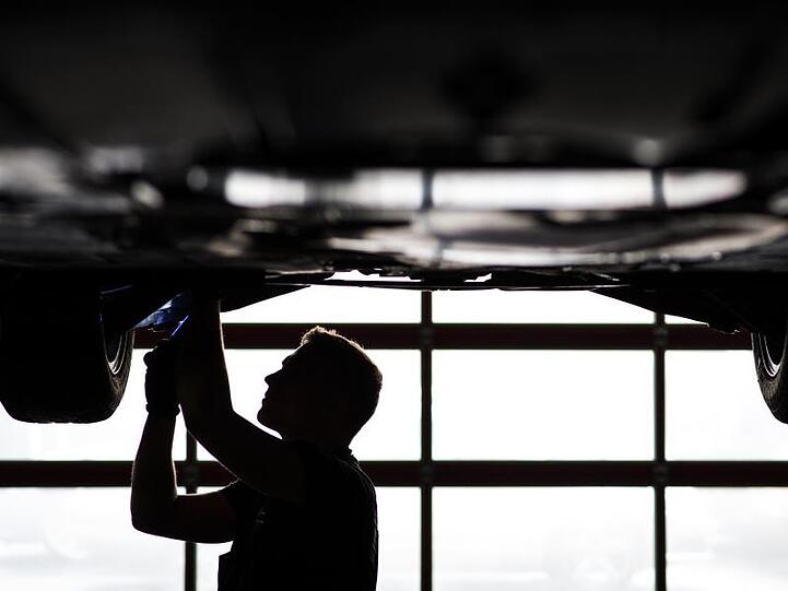 Ein Mechaniker arbeitet in einer KfZ-Werkstatt an einem Auto. Foto: David-Wolfgang Ebener/dpa/Symbolbild