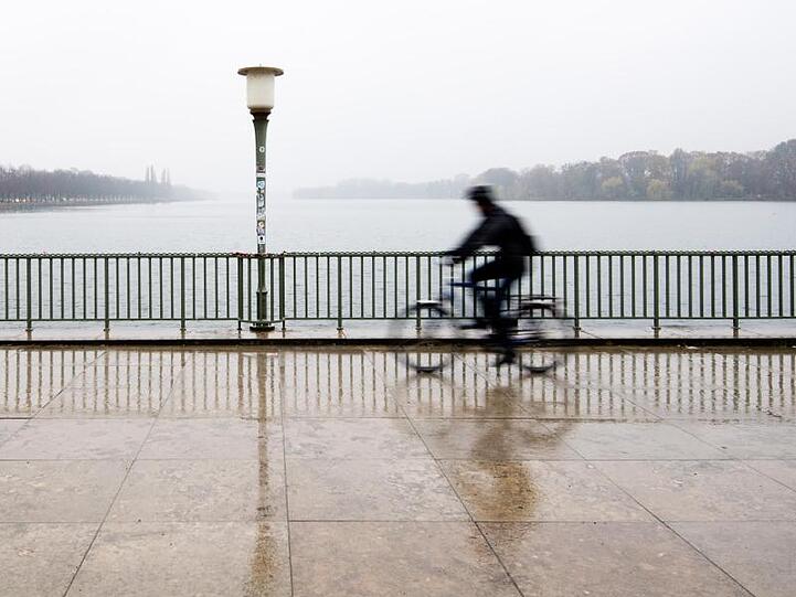 Ein Radfahrer fährt bei verregnetem Wetter und Temperaturen knapp über dem Gefrierpunkt am Maschsee in Hannover entlang.
