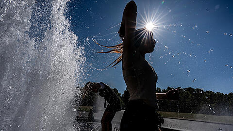 02.07.2025, Berlin: Touristen stehen im Brunnen im Lustgarten . Hitze und Temperaturen von mehr als 30 Grad werden in der Hauptstadt erwartet. Foto: Michael Kappeler/dpa +++ dpa-Bildfunk +++