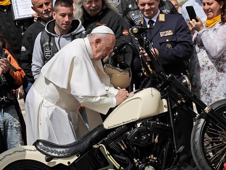 Papst Franziskus unterschreibt auf einer Harley-Davidson, während er Mitglieder der Gruppe "Jesus Bikers International" auf dem Petersplatz trifft.