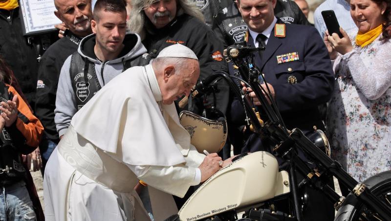 Papst Franziskus unterschreibt auf einer Harley-Davidson, während er Mitglieder der Gruppe "Jesus Bikers International" auf dem Petersplatz trifft. Papst Franziskus unterschreibt auf einer Harley-Davidson, während er Mitglieder der Gruppe "Jesus Bikers International" auf dem Petersplatz trifft.