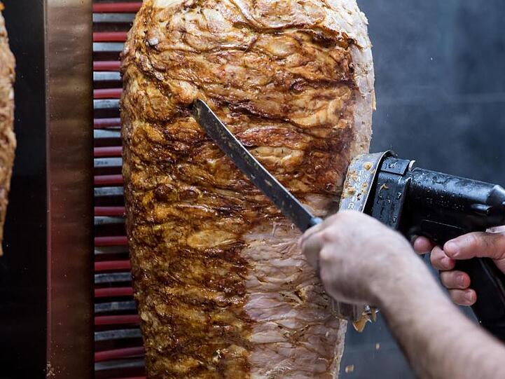 Ein Mann schneidet an einem Dönerspieß. Foto: Sven Hoppe