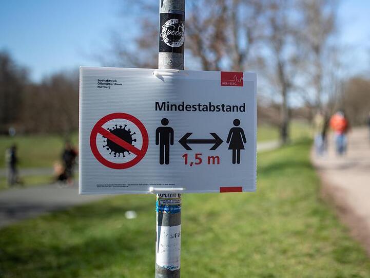 "Mindestabstand 1,5 Meter" zwischen Personen wegen des Coronavirus steht auf einem Schild am Rande eines Gehweges. Foto: Daniel Karmann/dpa