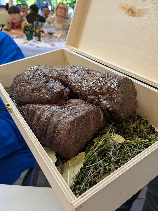 Das ger&auml;ucherte Filet vom Steirischen Almochsen wird in einer Holzbox am Tisch pr&auml;sentiert.