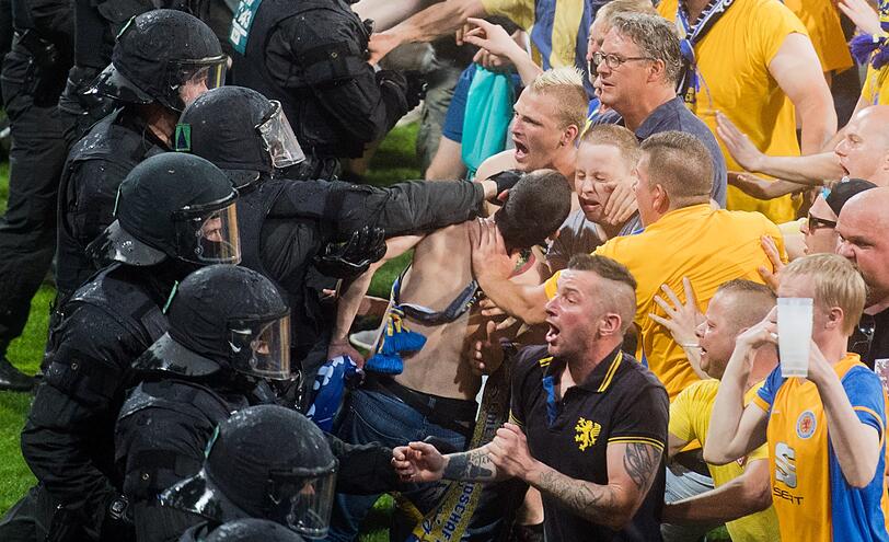 Braunschweiger Fans stehen Polizisten und Ordnern nach dem Abpfiff auf dem Platz gegenüber.