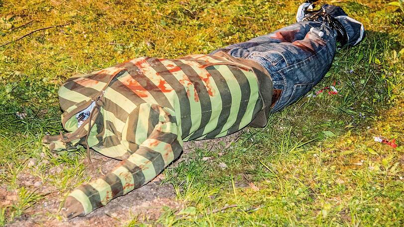 Weinstadt: Eine Puppe ohne Kopf liegt auf einer Wiese.