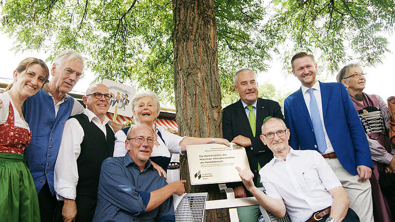 Die Tafel weist auf den neuen Schutzstatus des Viktualienmarktes hin. Im Bild v.l.: Ulrike Boesser, Ex Unesco Botschafter Hans-Heinrich Wredde, Jürgen Kirner, Marktsprecherin Elke Fett, Minister Ludwig Spaenle, Wolfgang Steffinger, Hans-Georg Küppers, Axel Markwardt.