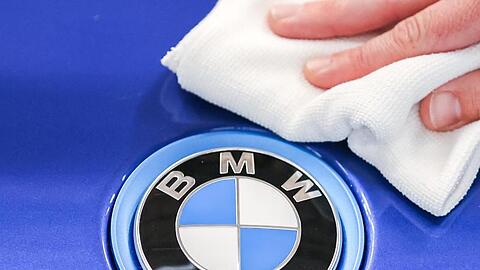 Ein Mitarbeiter von BMW poliert mit einem Tuch das Logo eines BMW i8. Foto: Jan Woitas/dpa-Zentralbild/dpa/Archivbild