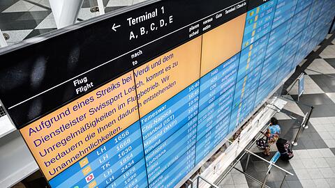 Eine Anzeigetafel am Münchner Flughafen weist auf Unregelmäßigkeiten im Flugbetrieb hin.