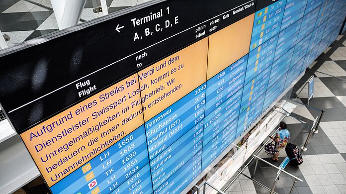 Eine Anzeigetafel am Münchner Flughafen weist auf Unregelmäßigkeiten im Flugbetrieb hin.