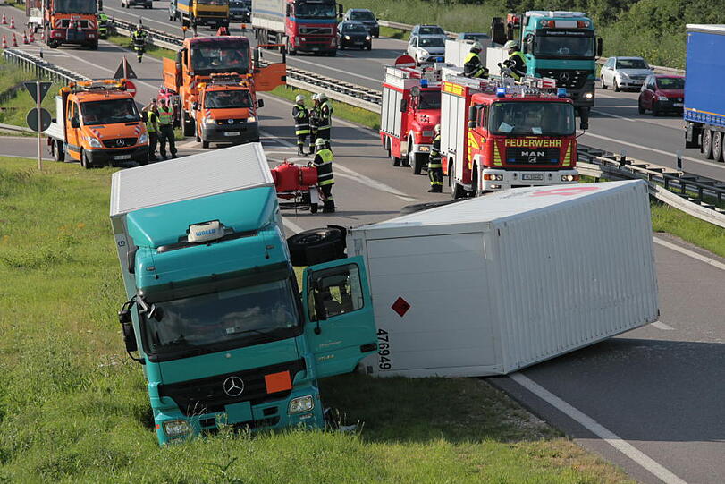 Vermutlich weil er zu schnell auf die Autobahn fährt, kommt ein Laster in der Kurve von der Fahrbahn ab und fährt in die Leitplanke. Sein Hänger kippt um.