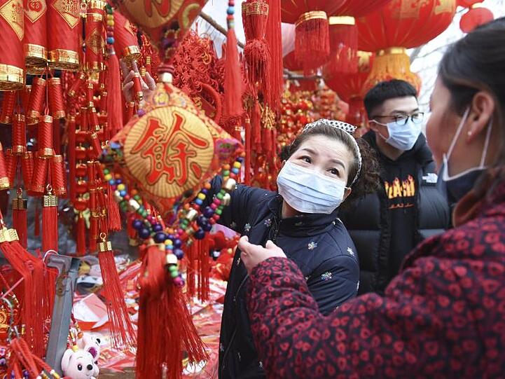 In der zentralchinesischen Provinz Anhui decken sich Menschen auf einem Markt mit Dekoration für das Neujahrsfest ein - und tragen Mundschutz.