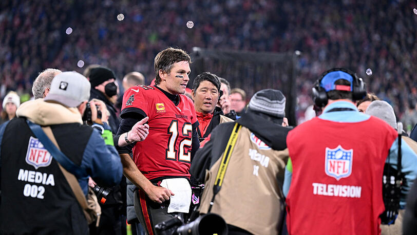 Tom Brady (M), Quarterback der Tampa Bay Buccaneers, läuft nach dem Spiel an Medienvertretern vorbei über den Rasen.