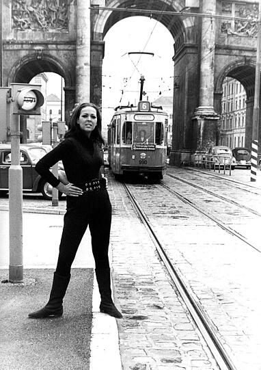 Emma-Peel-Doppelgängerin Friedel Frank vorm Siegestor mit Tram.
