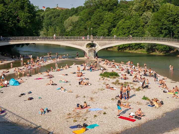 In München sonnen sich Badende auf einer Kiesbank in der Isar.