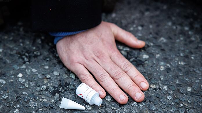 Ein Klimaaktivist hat sich mit der Hand auf einer Straße festgeklebt.