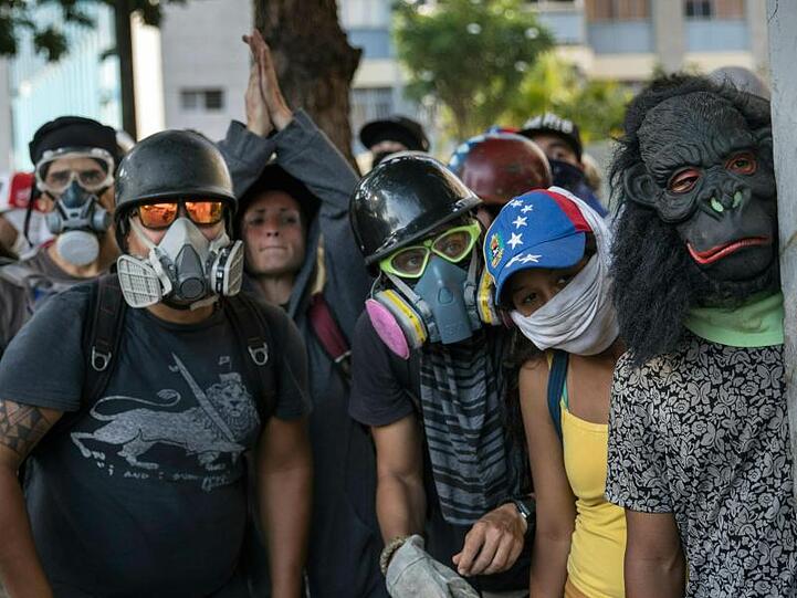 Regierungsgegner beobachten Sicherheitskräfte während Zusammenstößen in Caracas.