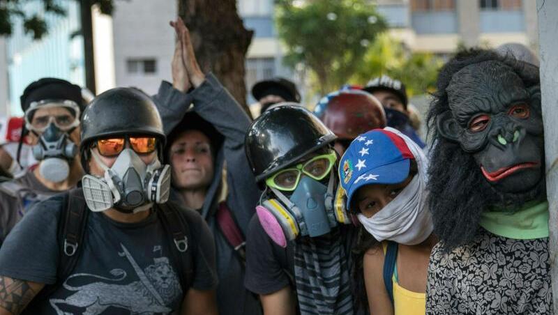 Regierungsgegner beobachten Sicherheitskräfte während Zusammenstößen in Caracas. Regierungsgegner beobachten Sicherheitskräfte während Zusammenstößen in Caracas.