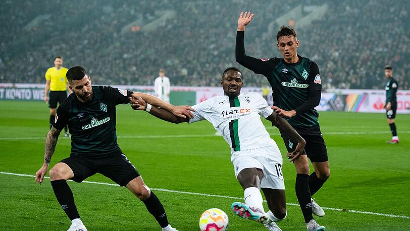 Gladbachs Marcus Thuram (M) kämpft mit Bremens Anthony Jung (l) und Fabio Chiarodia um den Ball.