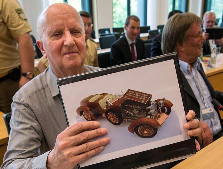 Roland S. bei seiner Anhöring im Landtag Ende Juni. Er zeigt ein Bild eines der Modellautos, das er Hubert Haderthauer gebaut hat.