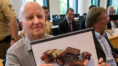 Roland S. bei seiner Anhöring im Landtag Ende Juni. Er zeigt ein Bild eines der Modellautos, das er Hubert Haderthauer gebaut hat.