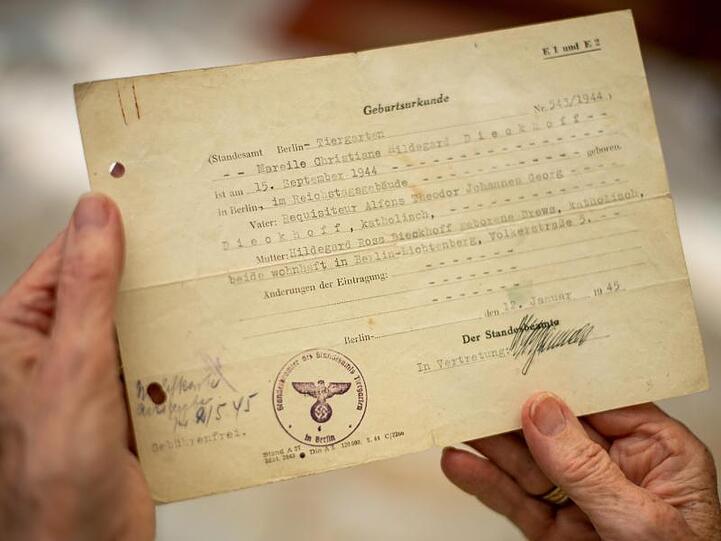 Mareile Van der Wyst, geboren am 15. September 1944 im Keller des Reichstages, hält ihre Geburtsurkunde in den Händen.