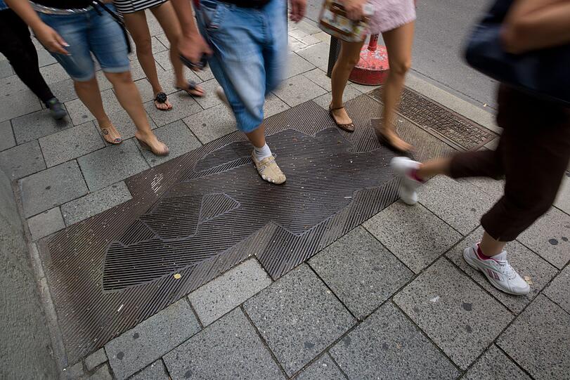 Tatortbild in Stahl: Die eher unauffällige Platte in der Kardinal-Faulhaber-Straße, geschaffen von Erika Maria Lankes.