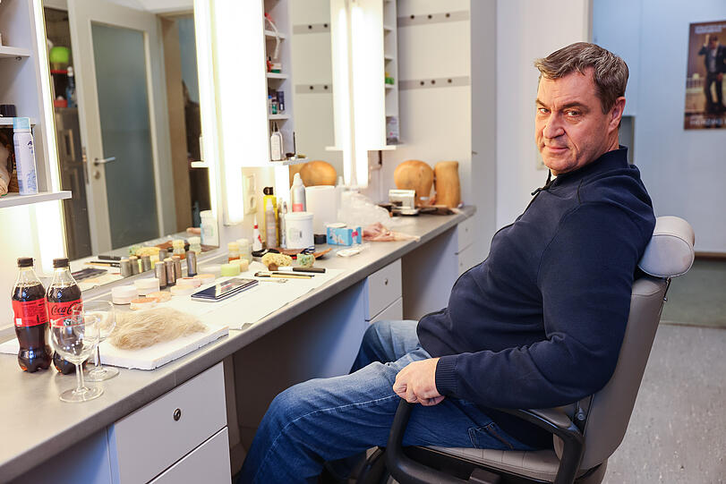 Bayerns Ministerpräsident Markus Söder (CSU) sitzt noch unverkleidet in der Maske im Staatstheater Nürnberg.