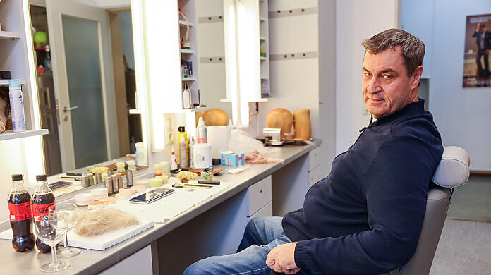 Bayerns Ministerpräsident Markus Söder (CSU) sitzt noch unverkleidet in der Maske im Staatstheater Nürnberg.