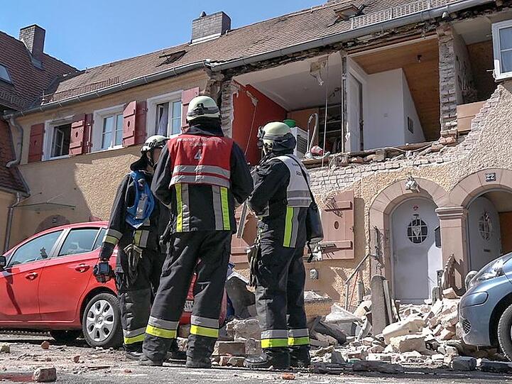 Feuerwehrleute stehen vor einem Haus in Nürnberg, dessen Fassade teilweise weggesprengt wurde.