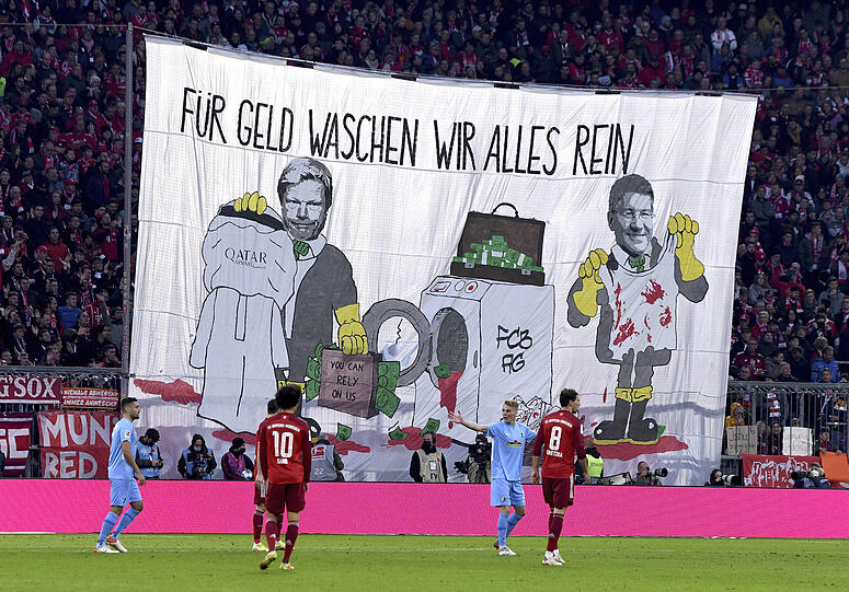 November 2021: Vorstandsboss Oliver Kahn und Präsident Herbert Hainer auf einem großen Protestplakat beim Waschen blutverschmierter Kleidung. "Für Geld waschen wir alles rein", steht darüber geschrieben.
