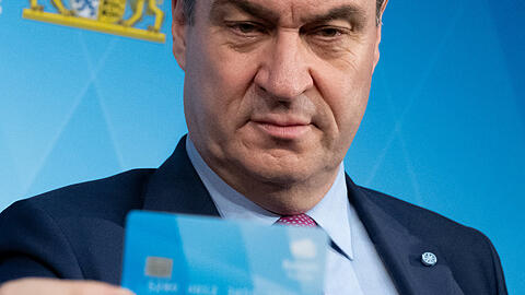 Bayerns Ministerpräsident Markus Söder hält eine Bezahlkarte.